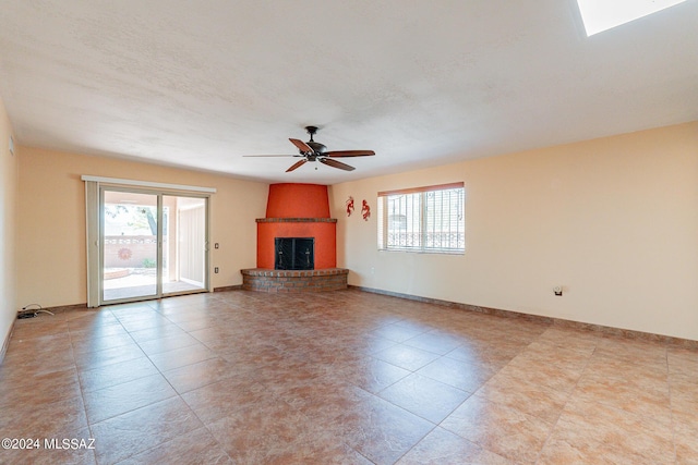 unfurnished living room with ceiling fan, a fireplace, baseboards, and a textured ceiling