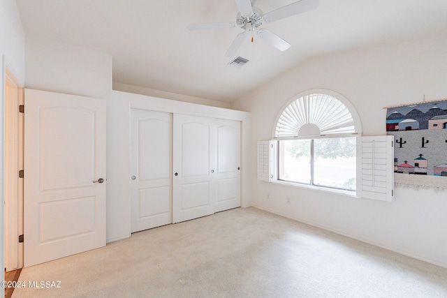 unfurnished bedroom featuring ceiling fan, a closet, light carpet, and lofted ceiling