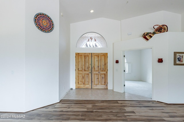 foyer entrance with hardwood / wood-style floors and high vaulted ceiling