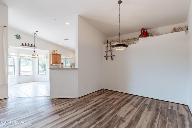 unfurnished dining area featuring hardwood / wood-style floors and vaulted ceiling