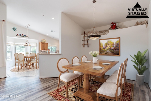 dining room featuring a chandelier, light hardwood / wood-style floors, and vaulted ceiling