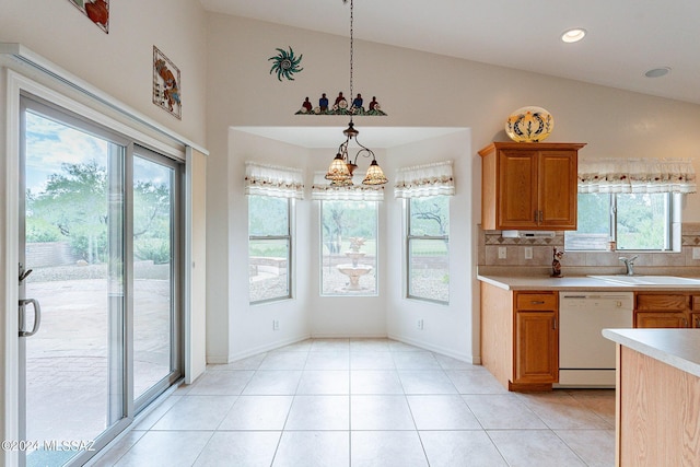 kitchen featuring white dishwasher, pendant lighting, a chandelier, lofted ceiling, and decorative backsplash