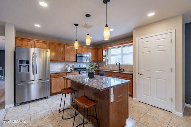 kitchen featuring pendant lighting, a center island, sink, dark stone countertops, and stainless steel appliances