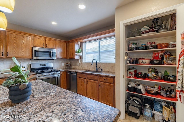 kitchen with decorative backsplash, sink, dark stone counters, and appliances with stainless steel finishes