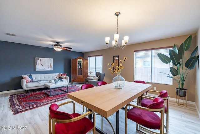 dining room with ceiling fan with notable chandelier and light wood-type flooring