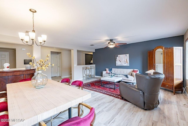 dining space featuring ceiling fan with notable chandelier and light hardwood / wood-style flooring