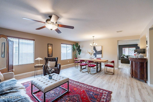 living room featuring a textured ceiling, ceiling fan with notable chandelier, and light hardwood / wood-style flooring