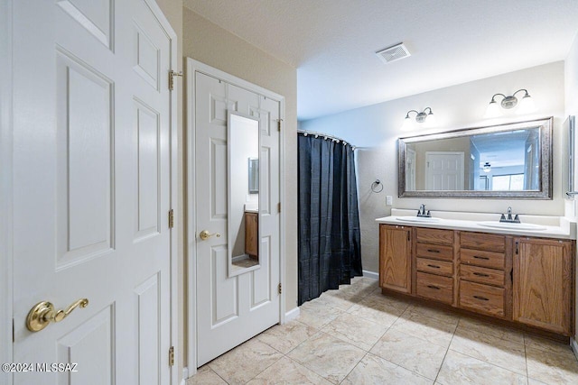 bathroom with tile patterned flooring, vanity, and a textured ceiling