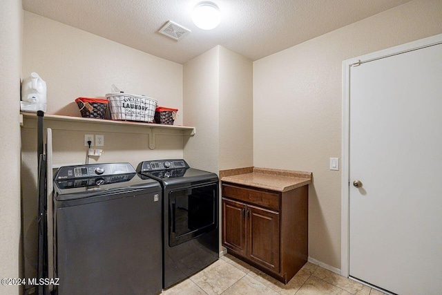 washroom with washer and dryer, cabinets, light tile patterned floors, and a textured ceiling