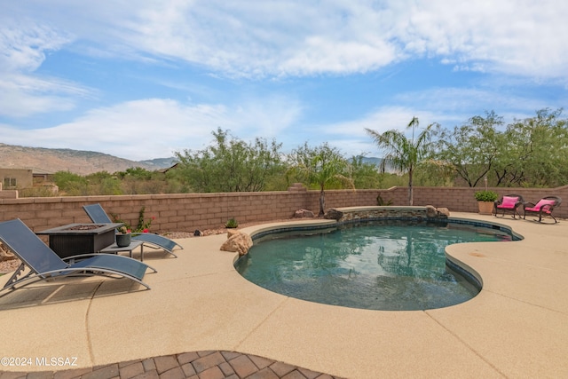 view of swimming pool with a patio, a mountain view, and a fire pit