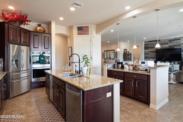 kitchen with dark brown cabinets, sink, an island with sink, hanging light fixtures, and appliances with stainless steel finishes