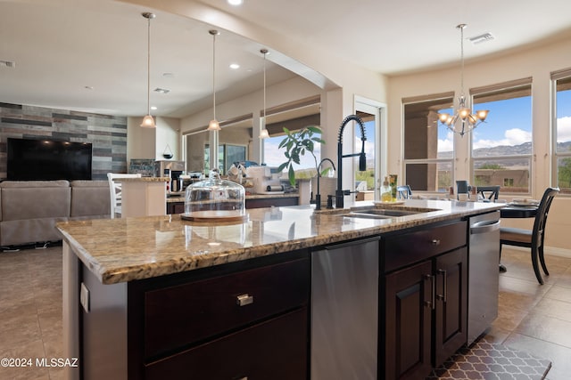 kitchen featuring an island with sink, light stone countertops, a chandelier, and a healthy amount of sunlight