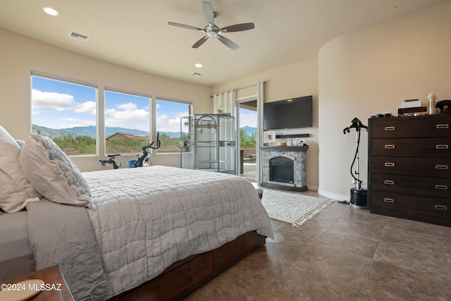 bedroom with a mountain view, ceiling fan, access to outside, and a fireplace