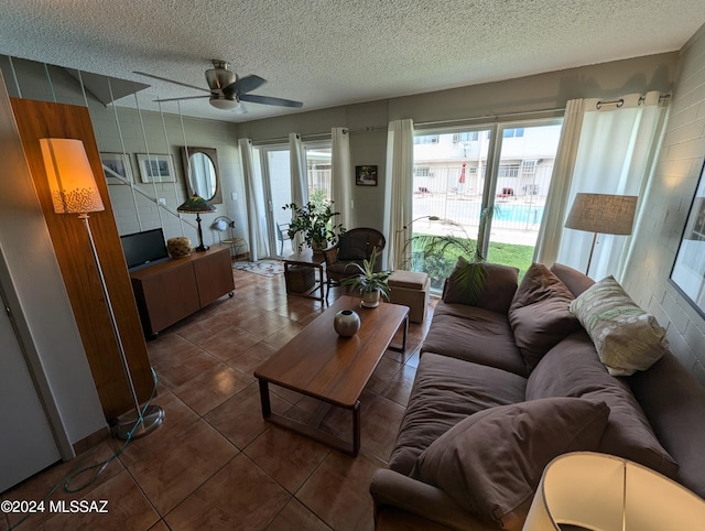 living room with a ceiling fan, dark tile patterned floors, and a textured ceiling