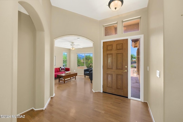 entrance foyer featuring ceiling fan, a towering ceiling, and wood-type flooring