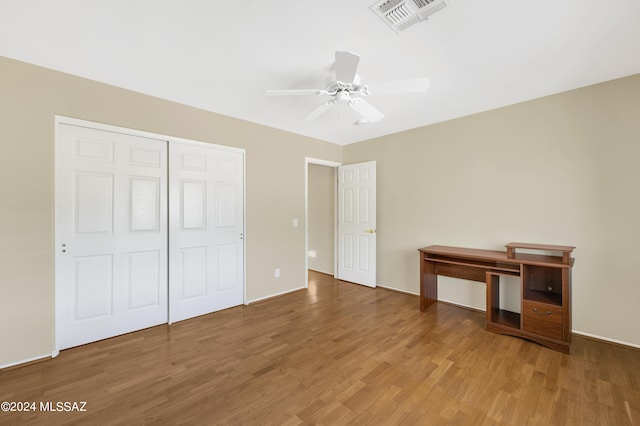 unfurnished bedroom with wood-type flooring, a closet, and ceiling fan