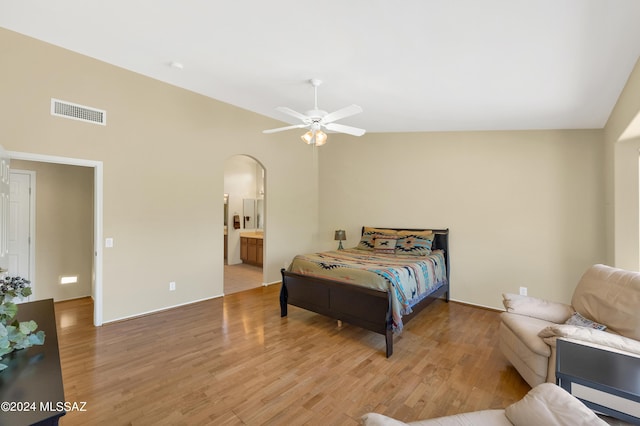 bedroom with connected bathroom, ceiling fan, light hardwood / wood-style flooring, and vaulted ceiling