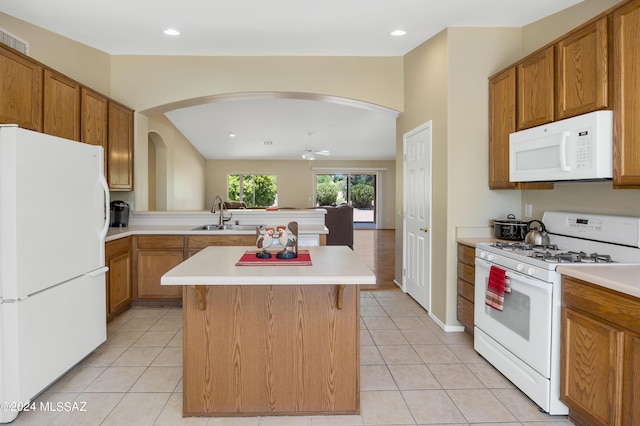 kitchen featuring a center island, white appliances, sink, ceiling fan, and light tile patterned flooring