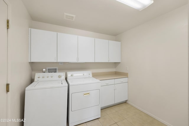 laundry room featuring cabinets, washing machine and dryer, and light tile patterned floors