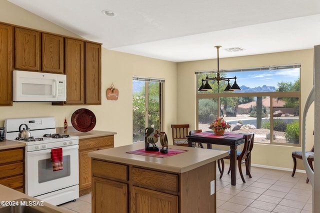 kitchen with white appliances, light tile patterned floors, an inviting chandelier, a center island, and hanging light fixtures