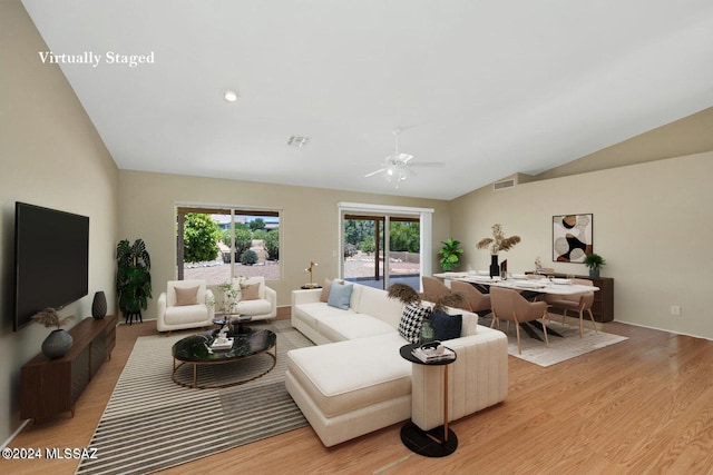 living room featuring light hardwood / wood-style flooring, vaulted ceiling, and ceiling fan