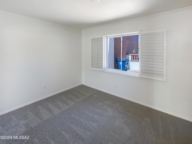 empty room featuring dark carpet and ornamental molding