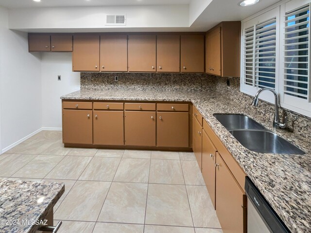 kitchen with light stone countertops, decorative backsplash, sink, and stainless steel dishwasher