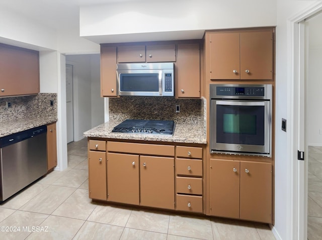 kitchen with light tile patterned floors, appliances with stainless steel finishes, and tasteful backsplash