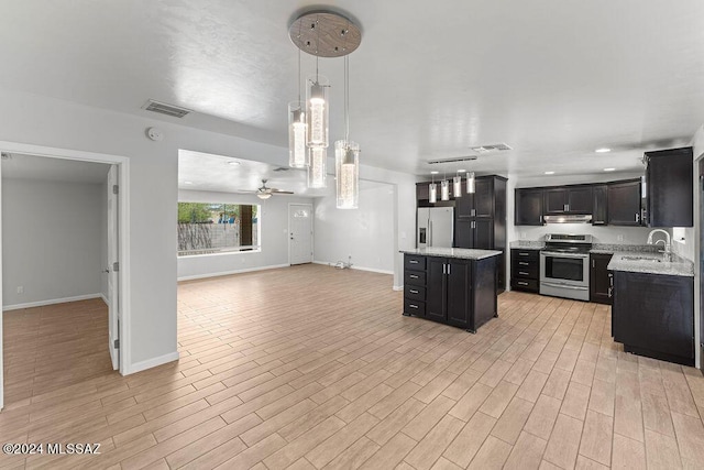 kitchen with pendant lighting, sink, ceiling fan, a kitchen island, and stainless steel appliances