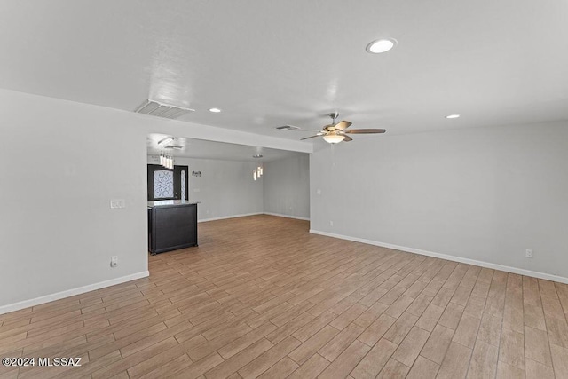 unfurnished living room featuring ceiling fan with notable chandelier