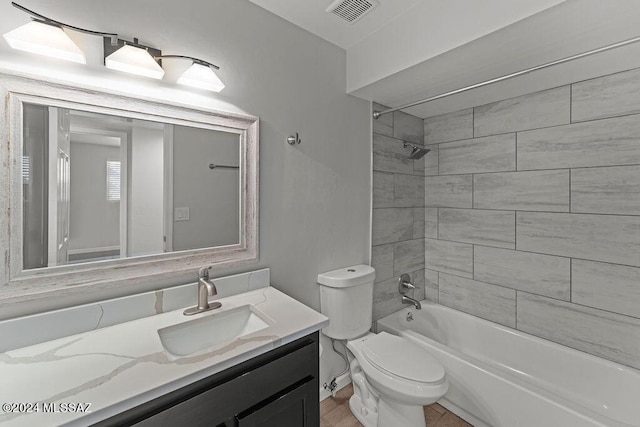 full bathroom with vanity, tiled shower / bath combo, and toilet