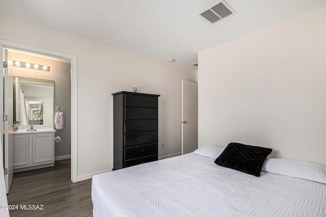 bedroom with dark hardwood / wood-style floors, sink, and ensuite bath