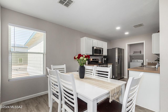 dining space with wood-type flooring, washer / dryer, and sink