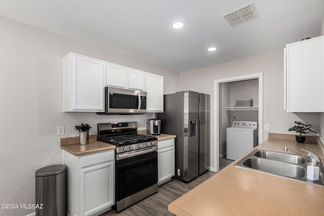 kitchen featuring washer / dryer, sink, appliances with stainless steel finishes, dark hardwood / wood-style flooring, and white cabinets