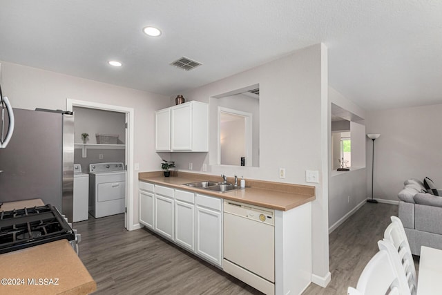 kitchen with white cabinetry, sink, hardwood / wood-style flooring, stainless steel appliances, and washing machine and dryer