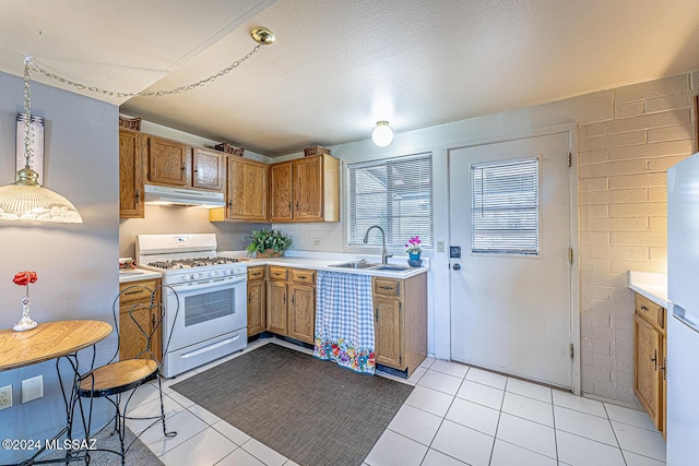 kitchen featuring sink, light tile patterned flooring, decorative light fixtures, and white appliances