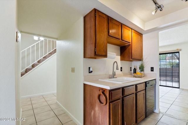 kitchen with rail lighting, sink, light tile patterned floors, and black dishwasher