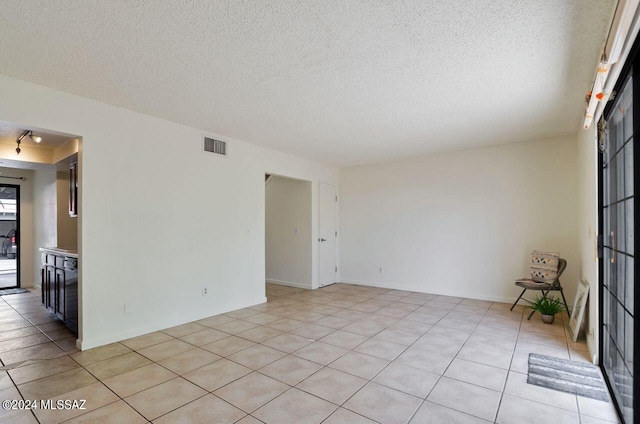 unfurnished room with light tile patterned flooring and a textured ceiling