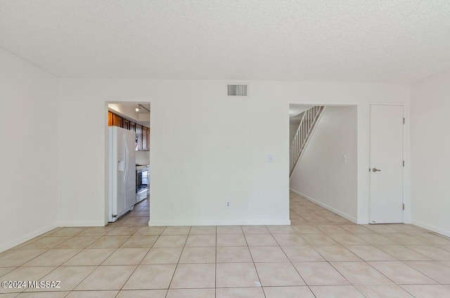 spare room with light tile patterned floors and a textured ceiling