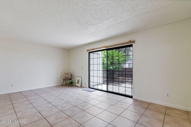 spare room featuring light tile patterned flooring and a textured ceiling