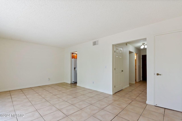 spare room featuring light tile patterned floors and a textured ceiling