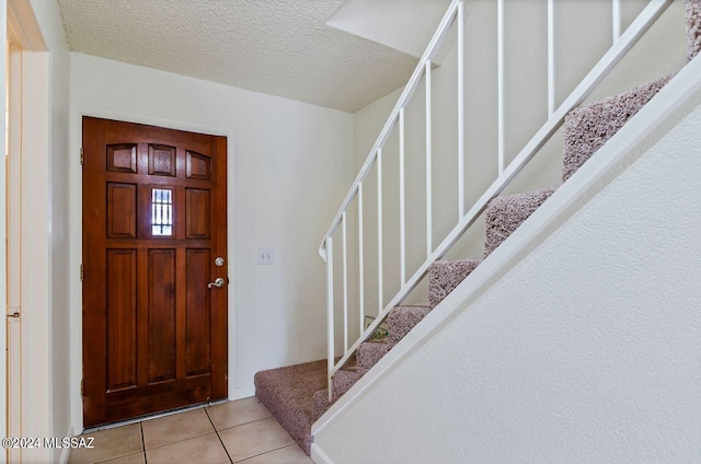 entrance foyer with light tile patterned floors and a textured ceiling