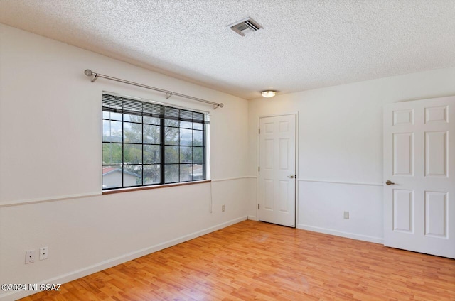 empty room with wood-type flooring and a textured ceiling