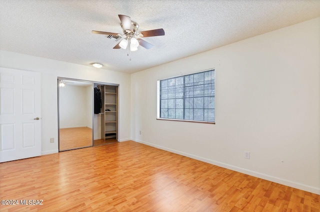 unfurnished bedroom featuring a closet, a textured ceiling, hardwood / wood-style flooring, and ceiling fan