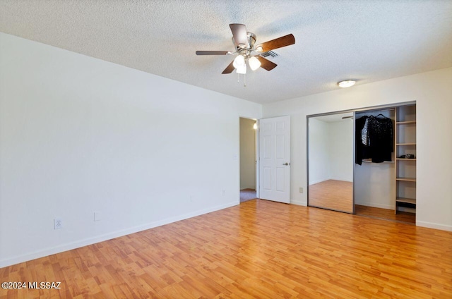 unfurnished bedroom with light wood-type flooring, a textured ceiling, a closet, and ceiling fan