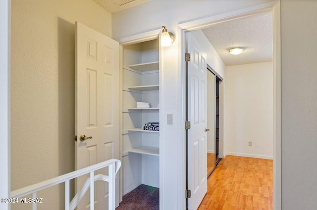 hall featuring a textured ceiling and light hardwood / wood-style floors