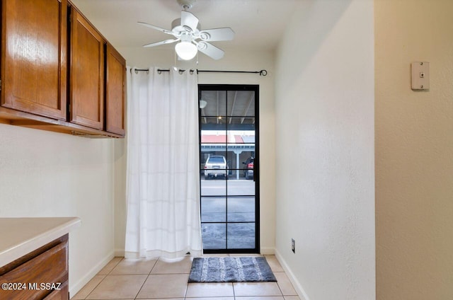 doorway to outside with ceiling fan and light tile patterned floors