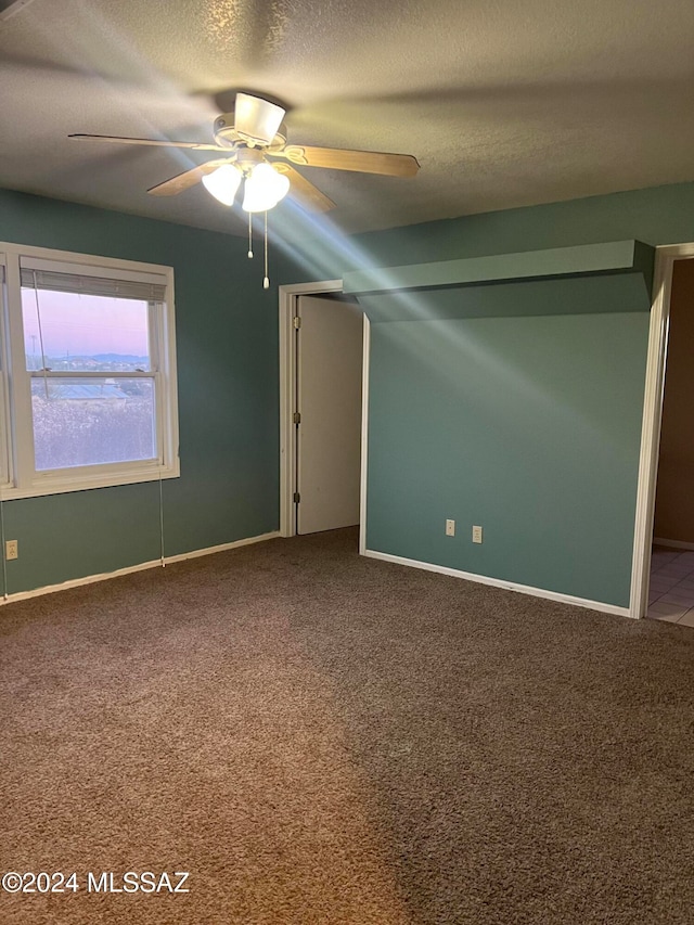 empty room with ceiling fan, carpet floors, and a textured ceiling