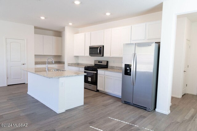 kitchen featuring appliances with stainless steel finishes, white cabinets, a kitchen island with sink, and sink