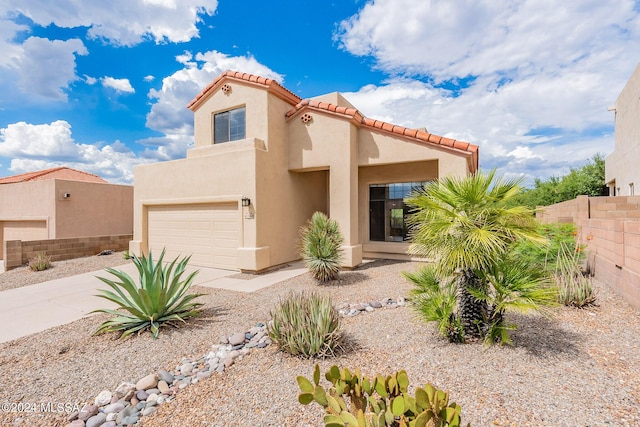 view of front of house featuring stucco siding, driveway, fence, an attached garage, and a tiled roof